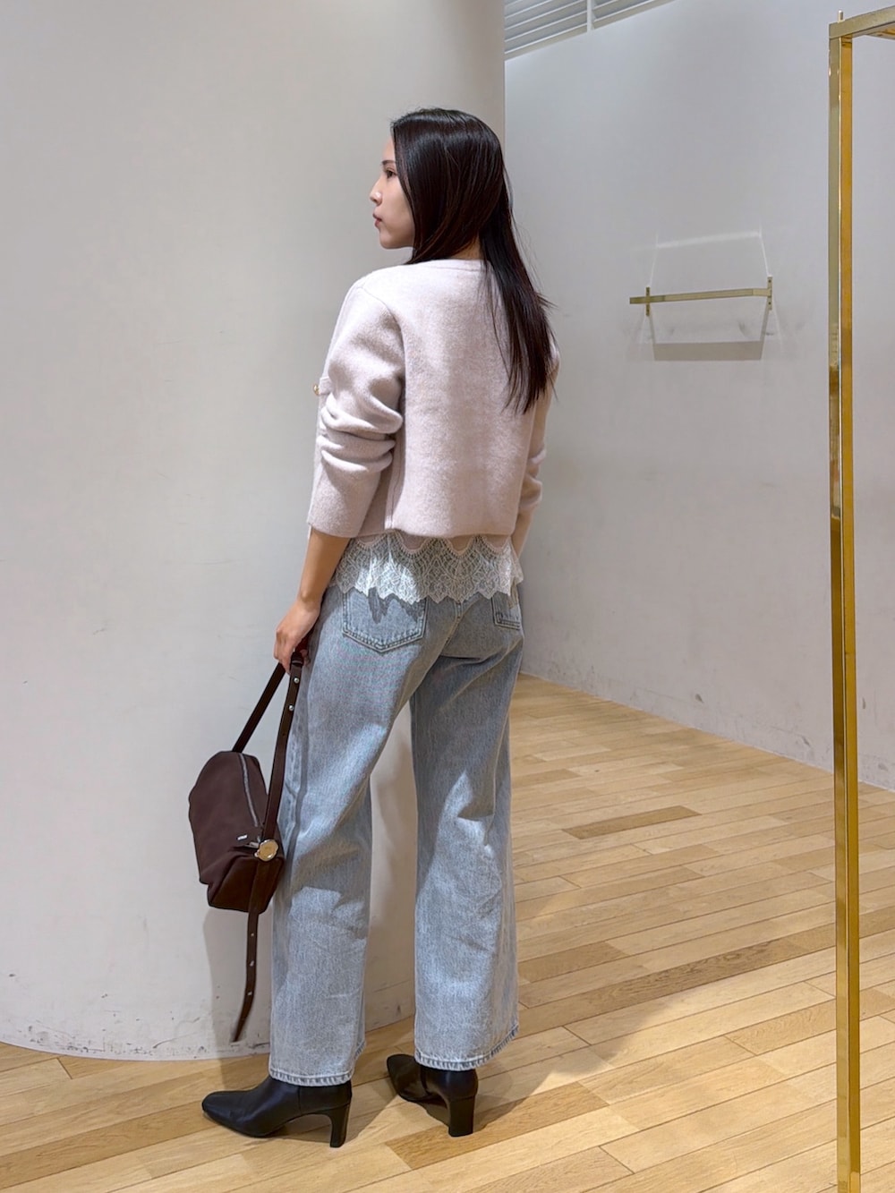 ベージュ系のノーカラージャケット、ベージュ系のキャミソール、ブルー系のデニムパンツを着用したレディースの秋コーディネートの3枚目の写真