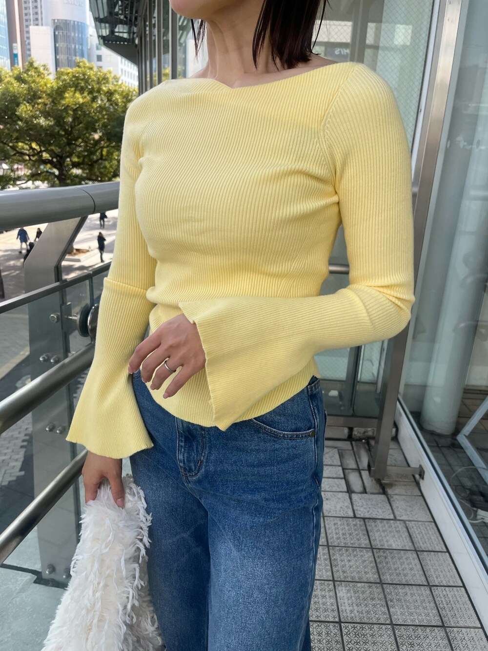 ブルー系のデニムパンツ、イエロー系のニット/セーター、ホワイト系のハンドバッグを着用したレディースの冬コーディネートの6枚目の写真