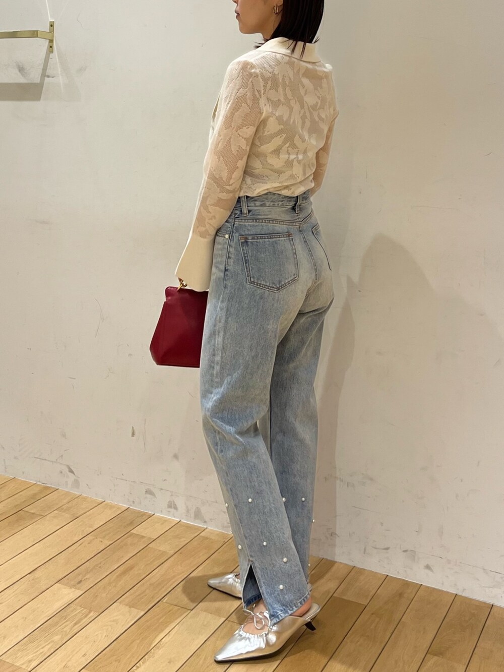 シルバー系のサンダル、ホワイト系のニット/セーター、ブルー系のデニムパンツを着用したレディースの春コーディネートの2枚目の写真