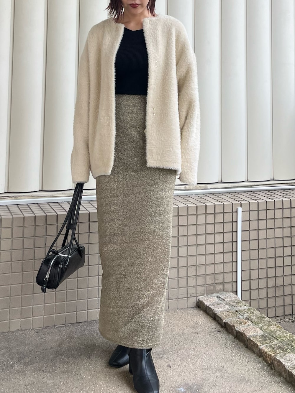 ホワイト系のカーディガン/ボレロ、ゴールド系のスカート、ブラック系のニット/セーターを着用したレディースの冬コーディネートの4枚目の写真