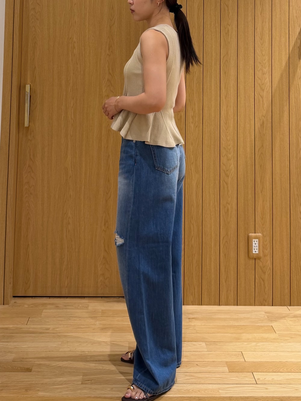 ブルー系のデニムパンツ、ベージュ系のニット/セーター、ブラウン系のサンダルを着用したレディースの夏コーディネートの2枚目の写真