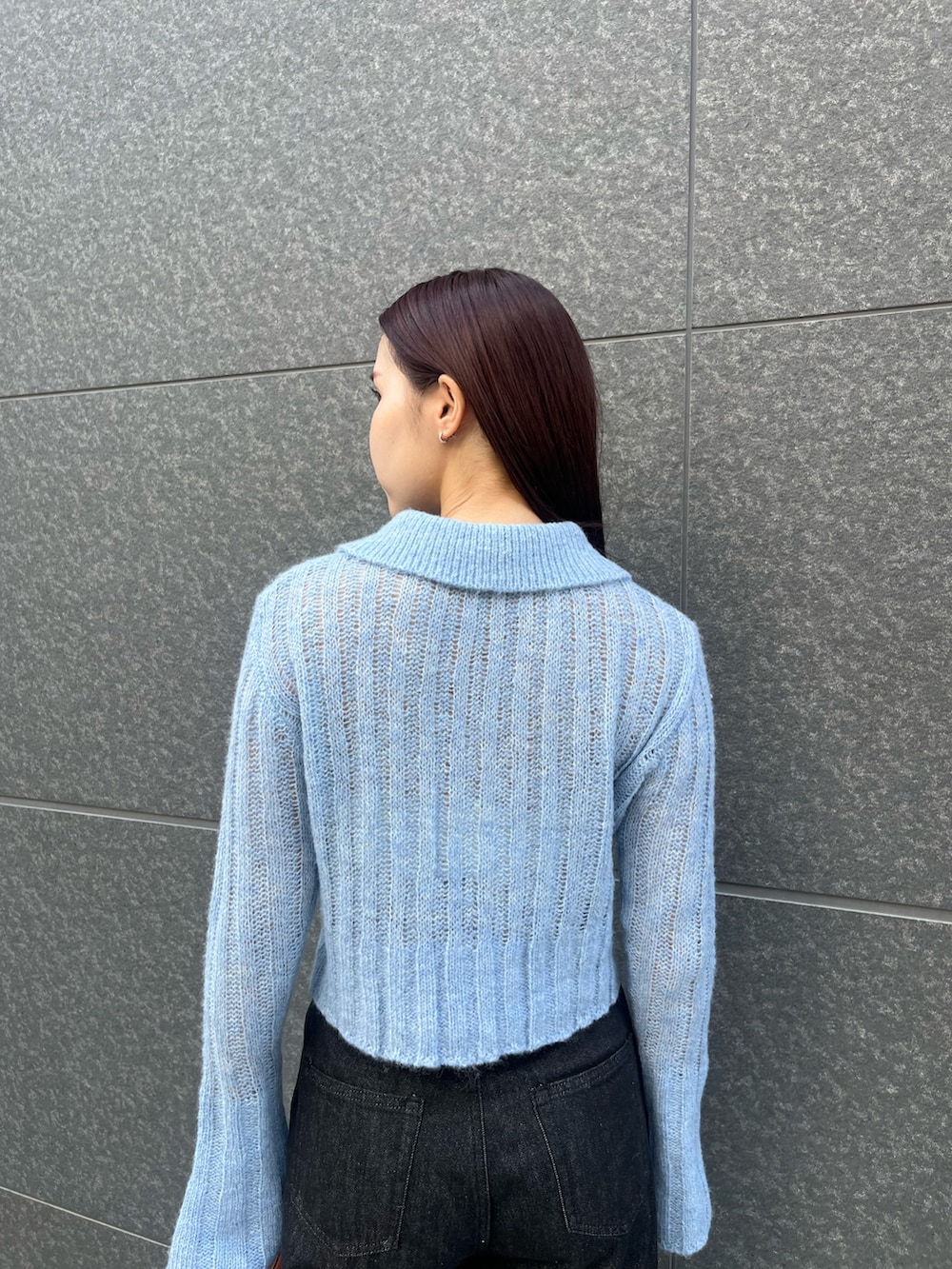 ブルー系のニット/セーター、ブラック系のデニムパンツ、ブラウン系のハンドバッグを着用したレディースの秋コーディネートの6枚目の写真