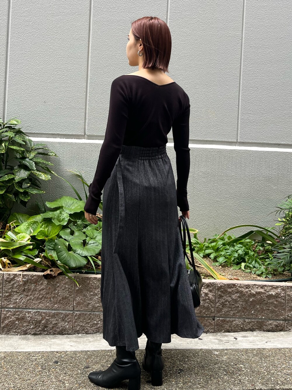 ブラック系のニット/セーター、グレー系のスカート、ブラック系のショルダーバッグを着用したレディースの秋コーディネートの3枚目の写真