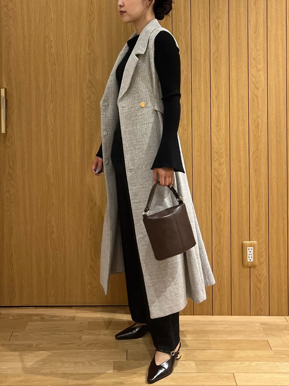 ブラウン系のハンドバッグ、ブラック系のデニムパンツ、グレー系のワンピースを着用したレディースの秋コーディネートの2枚目の写真