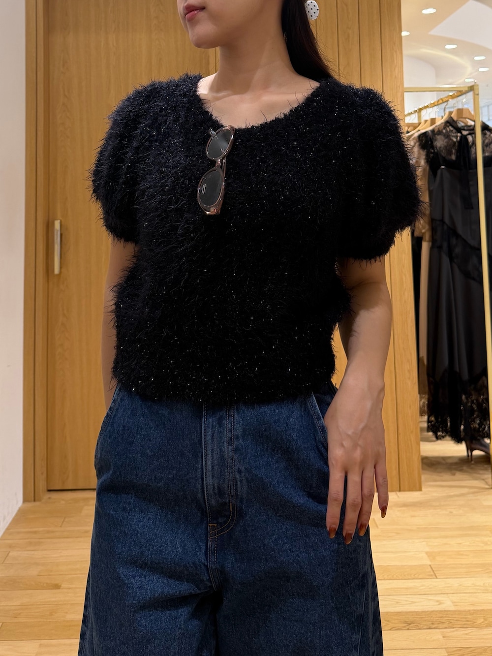ブルー系のデニムパンツ、ブラック系のニット/セーター、ブラック系のハンドバッグを着用したレディースの秋コーディネートの4枚目の写真