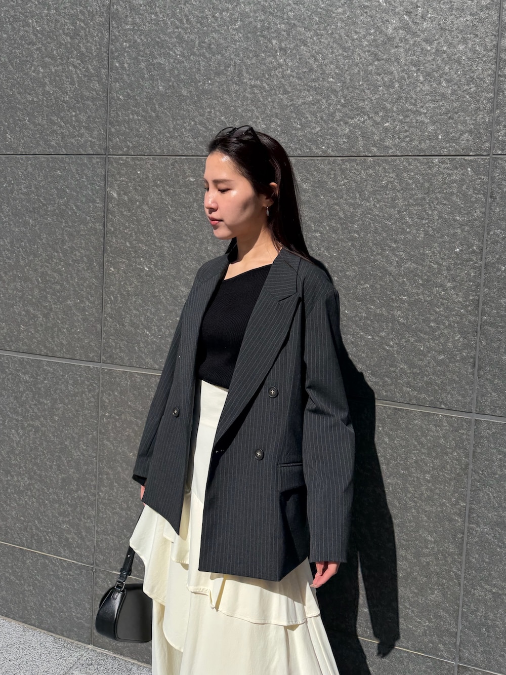 ホワイト系のスカート、ブラック系のニット/セーター、ブラック系のハンドバッグを着用したレディースの冬コーディネートの7枚目の写真