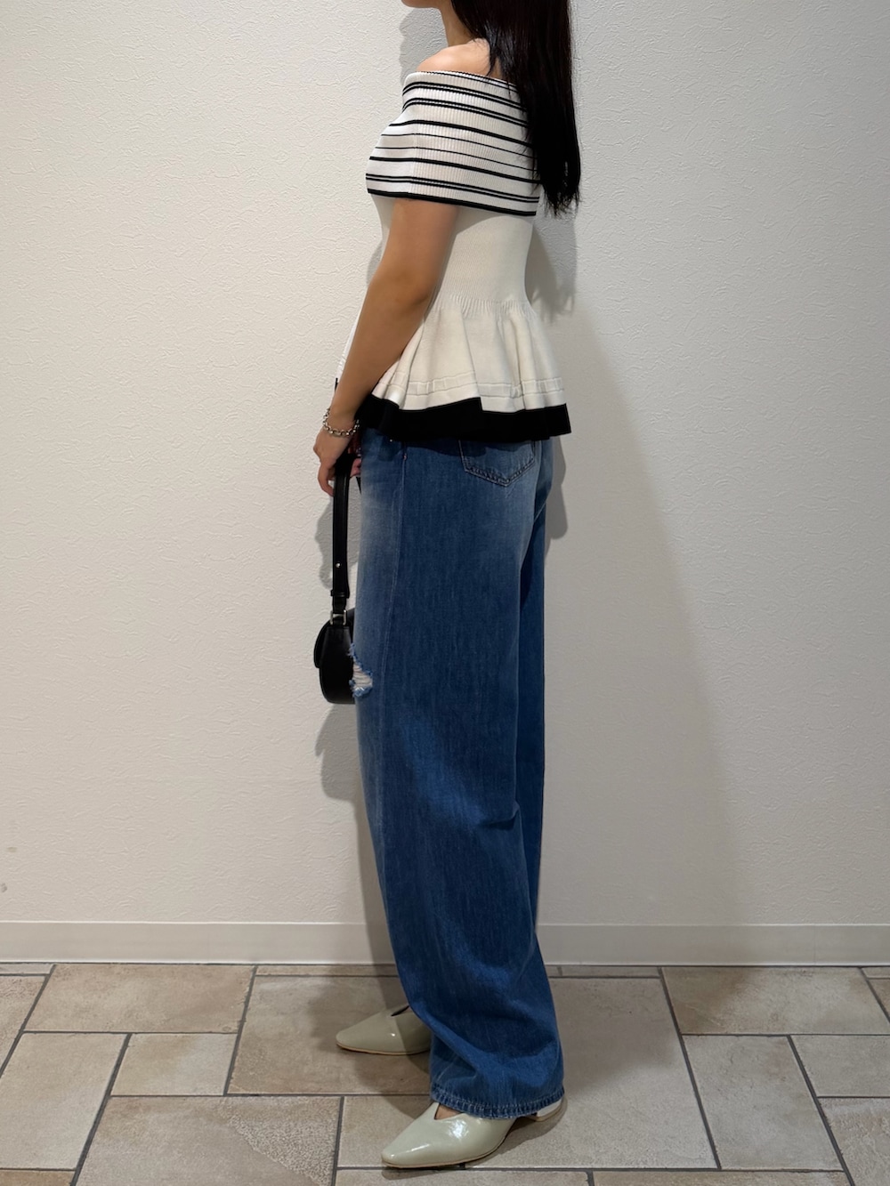 ブルー系のデニムパンツ、ブラック系のハンドバッグ、グリーン系のパンプスを着用したレディースの夏コーディネートの2枚目の写真