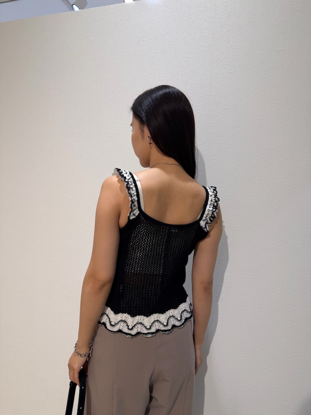 ベージュ系のその他パンツ、ブラック系のニット/セーター、ブラック系のハンドバッグを着用したレディースの夏コーディネートの6枚目の写真