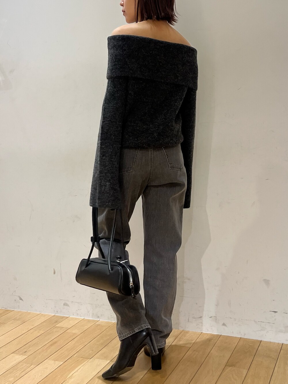ブラック系のデニムパンツ、グレー系のニット/セーター、ブラック系のショルダーバッグを着用したレディースの秋コーディネートの3枚目の写真