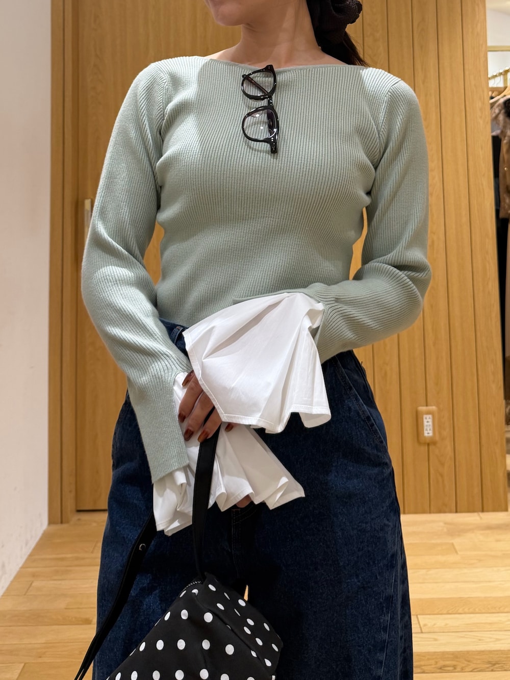 ブルー系のデニムパンツ、ブラック系のブーツ、ブラック系のハンドバッグを着用したレディースの秋コーディネートの4枚目の写真