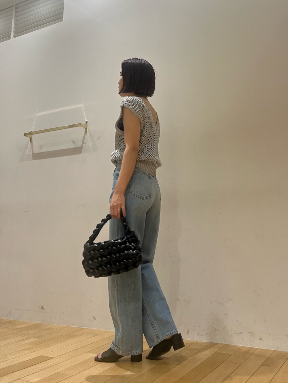 シルバー系のニット/セーター、ブルー系のデニムパンツ、ブラック系のハンドバッグを着用したレディースの夏コーディネートの2枚目の写真