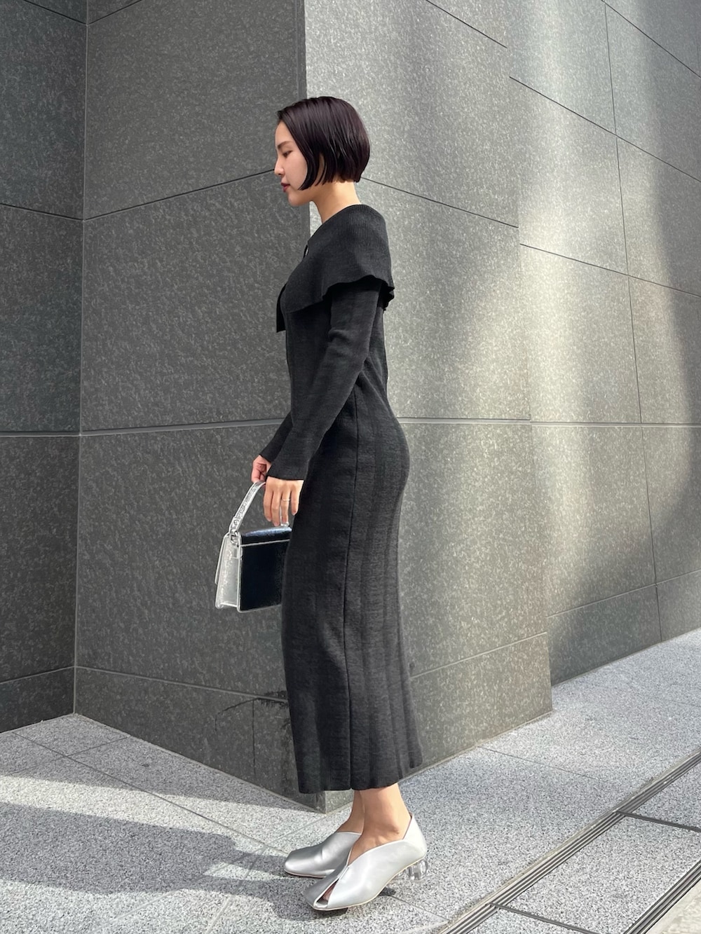 シルバー系のショルダーバッグ、シルバー系のパンプス、ブラック系のワンピースを着用したレディースの春コーディネートの2枚目の写真