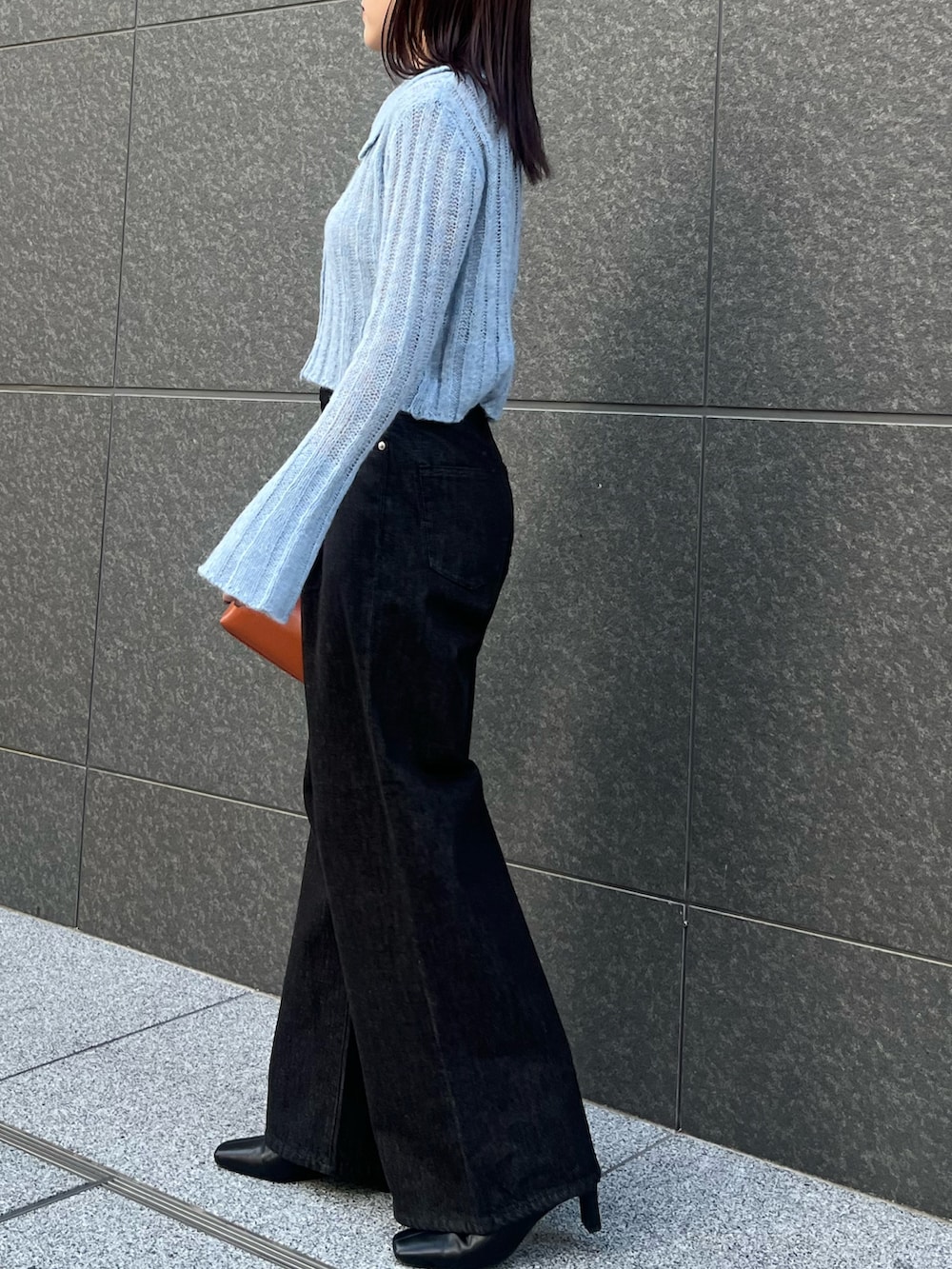 ブルー系のニット/セーター、ブラック系のデニムパンツ、ブラウン系のハンドバッグを着用したレディースの秋コーディネートの2枚目の写真