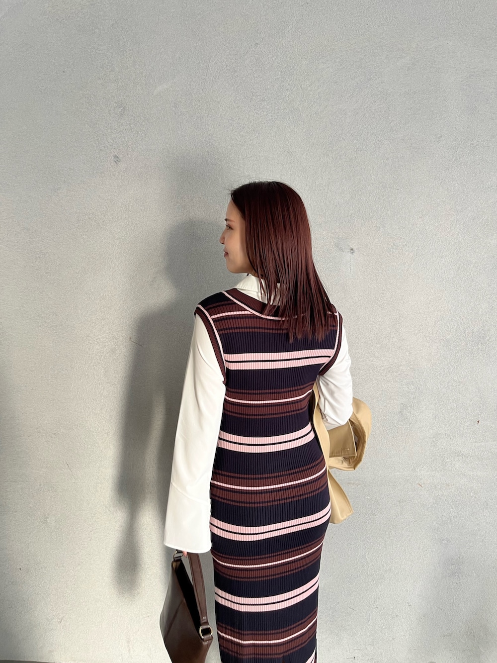 ブラウン系のハンドバッグ、ブラウン系のワンピース、ベージュ系のトレンチコートを着用したレディースの冬コーディネートの10枚目の写真