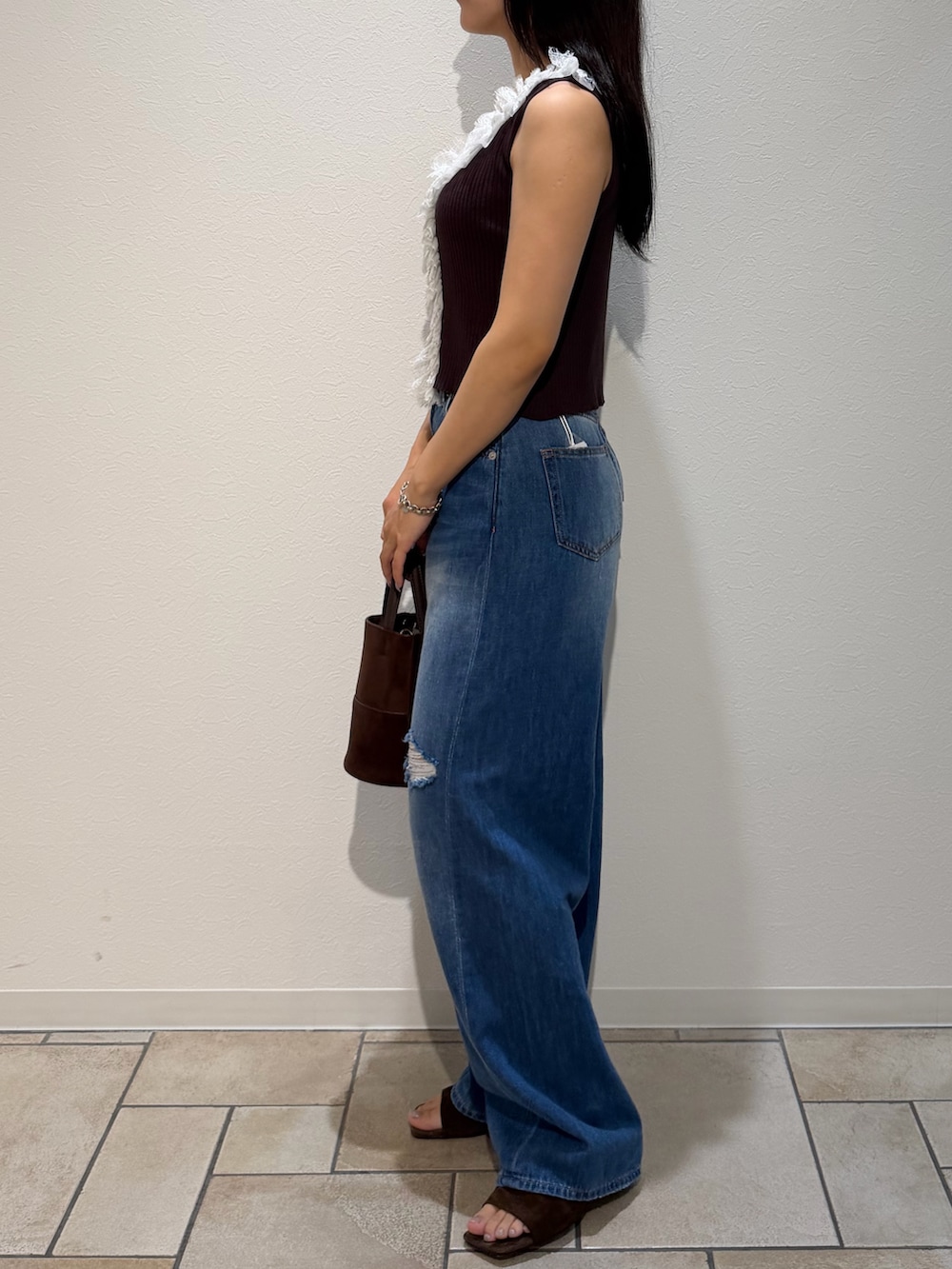 ブルー系のデニムパンツ、ブラウン系のサンダル、ブラウン系のハンドバッグを着用したレディースの夏コーディネートの2枚目の写真