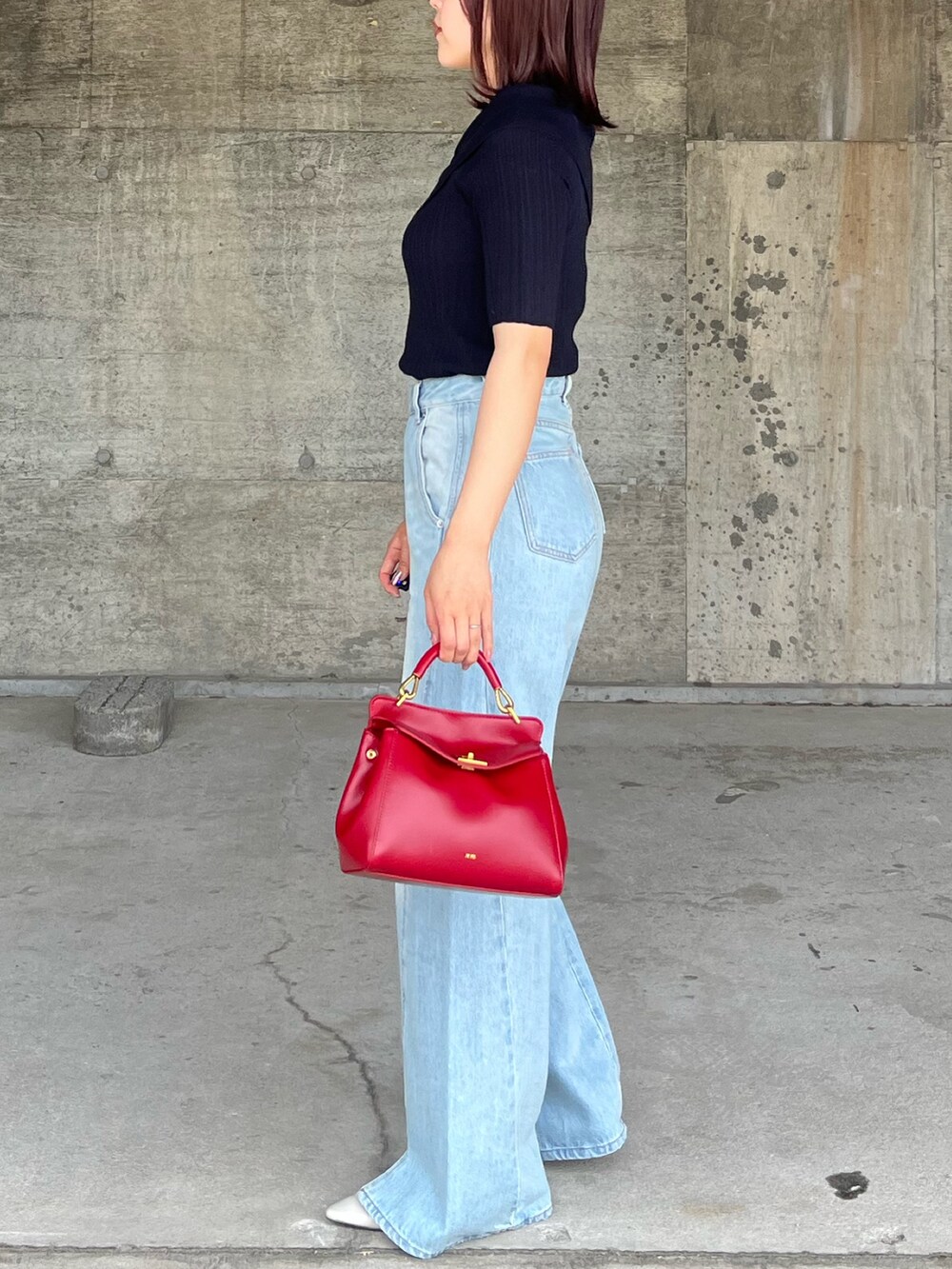 ブルー系のデニムパンツ、ブルー系のニット/セーター、レッド系のハンドバッグを着用したレディースの春コーディネートの2枚目の写真