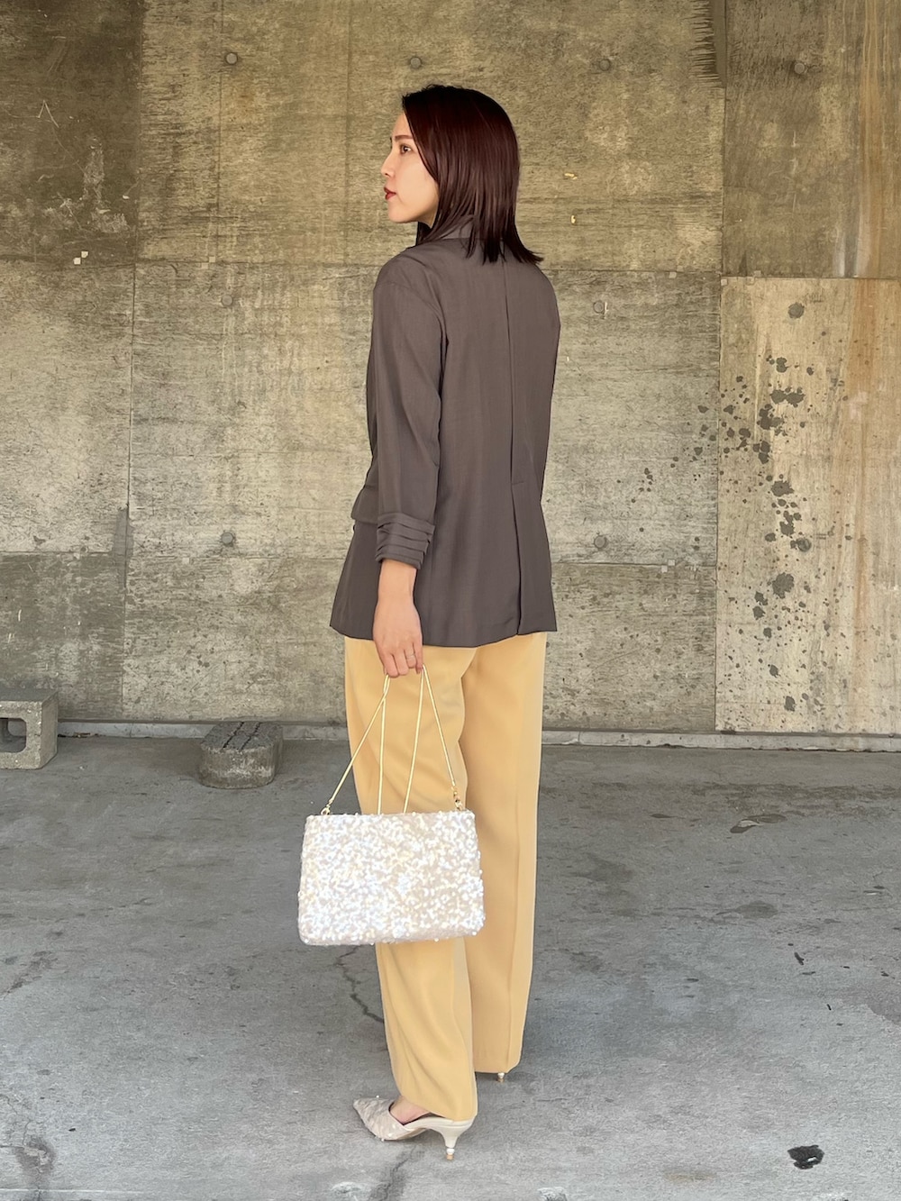 イエロー系のパンツドレス、ベージュ系のパンプス、ベージュ系のショルダーバッグを着用したレディースの春コーディネートの3枚目の写真
