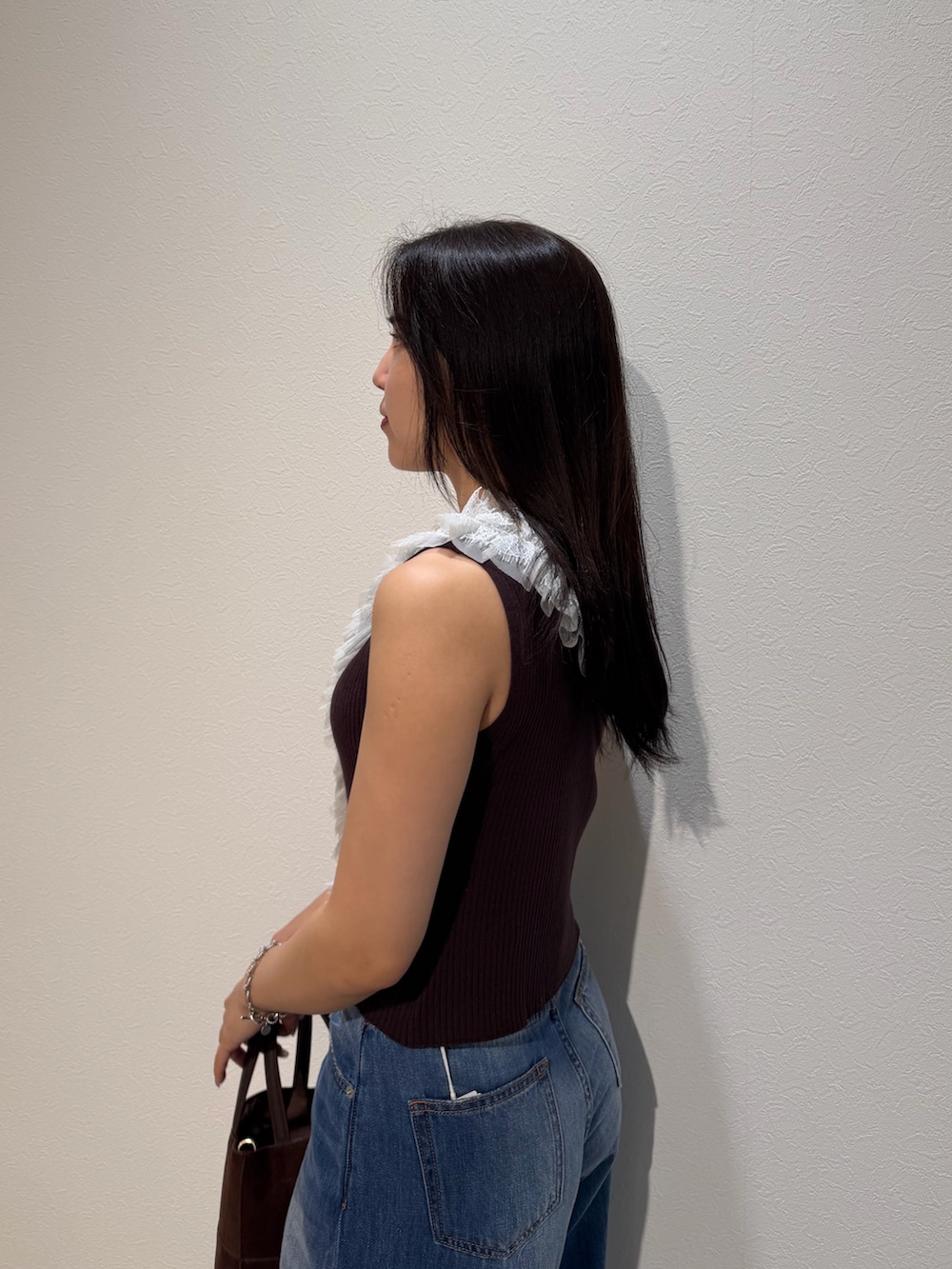 ブルー系のデニムパンツ、ブラウン系のサンダル、ブラウン系のハンドバッグを着用したレディースの夏コーディネートの5枚目の写真