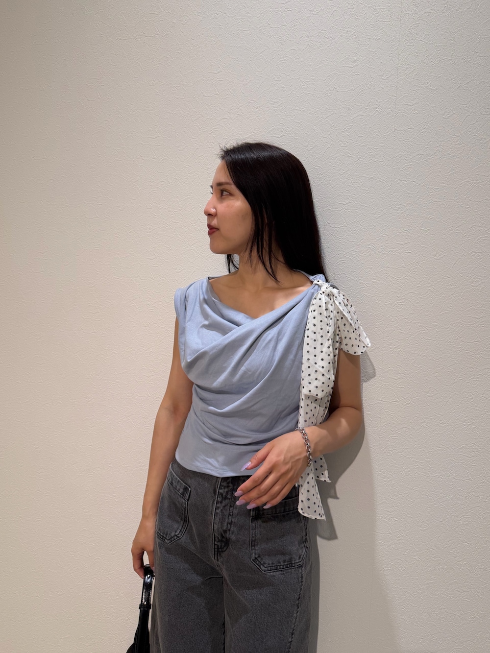 ブラック系のデニムパンツ、ブラック系のハンドバッグ、ブルー系のTシャツ/カットソーを着用したレディースの夏コーディネートの4枚目の写真