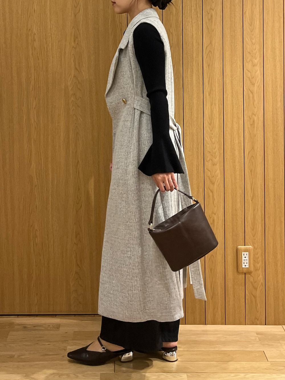 ブラウン系のハンドバッグ、ブラック系のデニムパンツ、グレー系のワンピースを着用したレディースの秋コーディネートの6枚目の写真