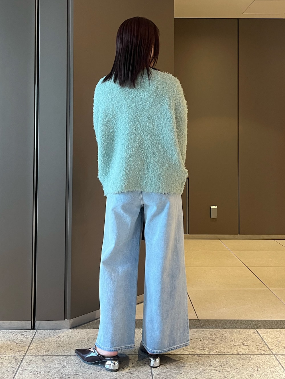 ブルー系のデニムパンツ、ブラウン系のパンプス、ブラウン系のボストンバッグを着用したレディースの夏コーディネートの3枚目の写真