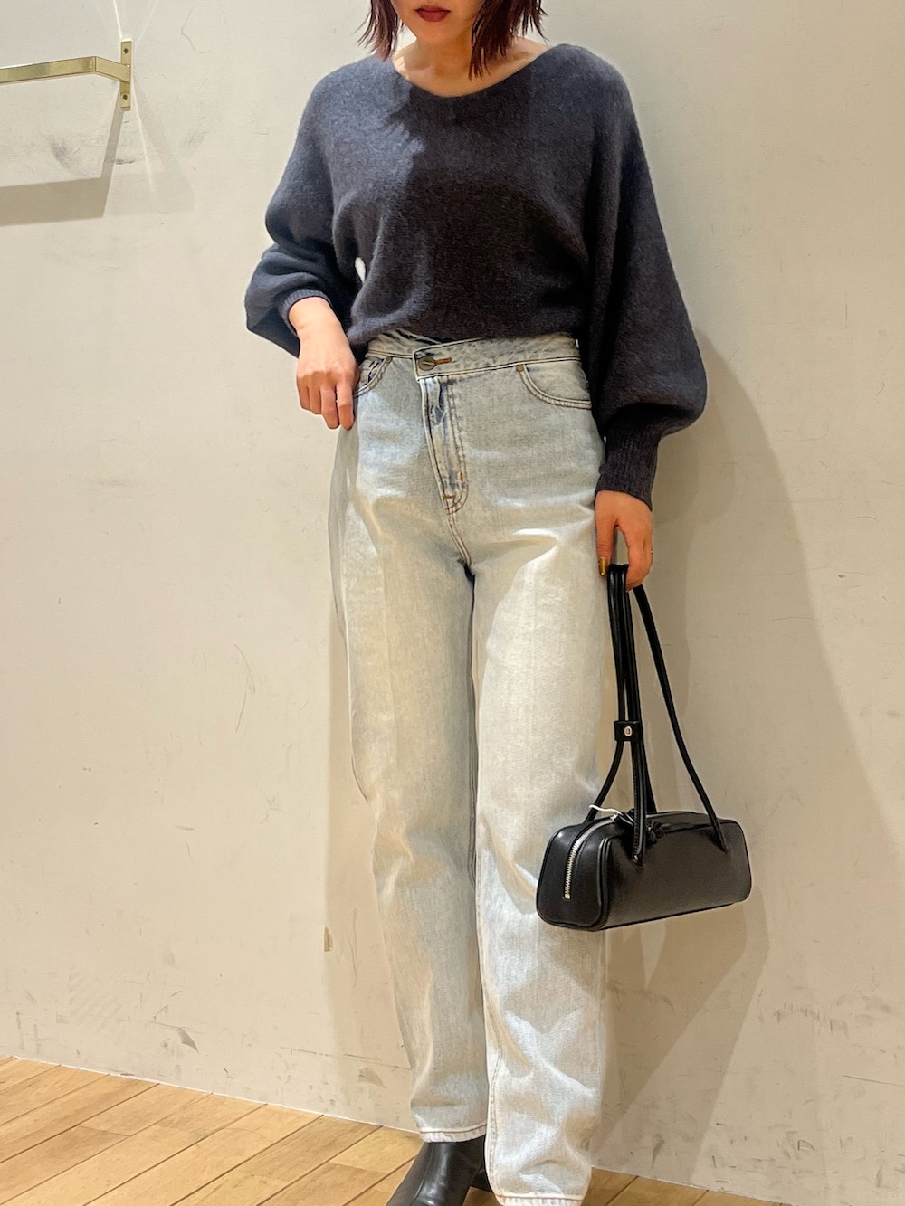 グレー系のニット/セーター、ブルー系のデニムパンツ、ブラック系のショルダーバッグを着用したレディースの秋コーディネートの4枚目の写真