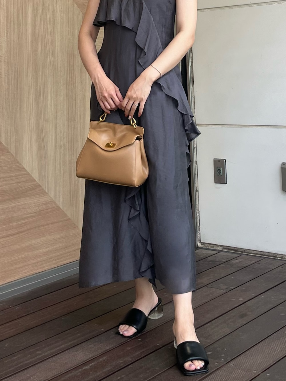 グレー系のワンピース、ブラウン系のハンドバッグ、ブラック系のサンダルを着用したレディースの夏コーディネートの7枚目の写真