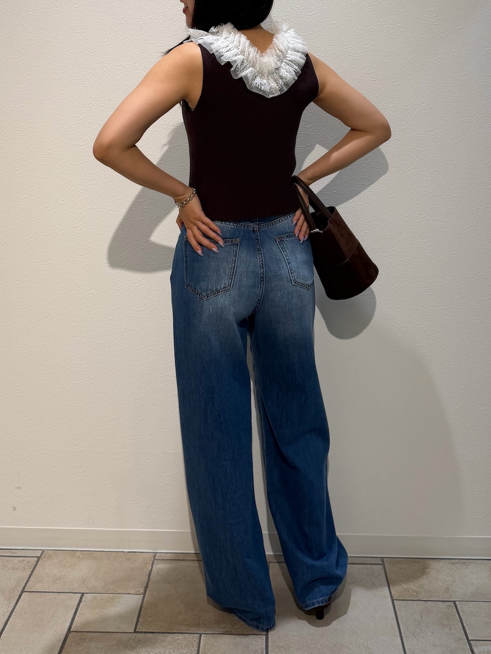 ブルー系のデニムパンツ、ブラウン系のサンダル、ブラウン系のハンドバッグを着用したレディースの夏コーディネートの3枚目の写真