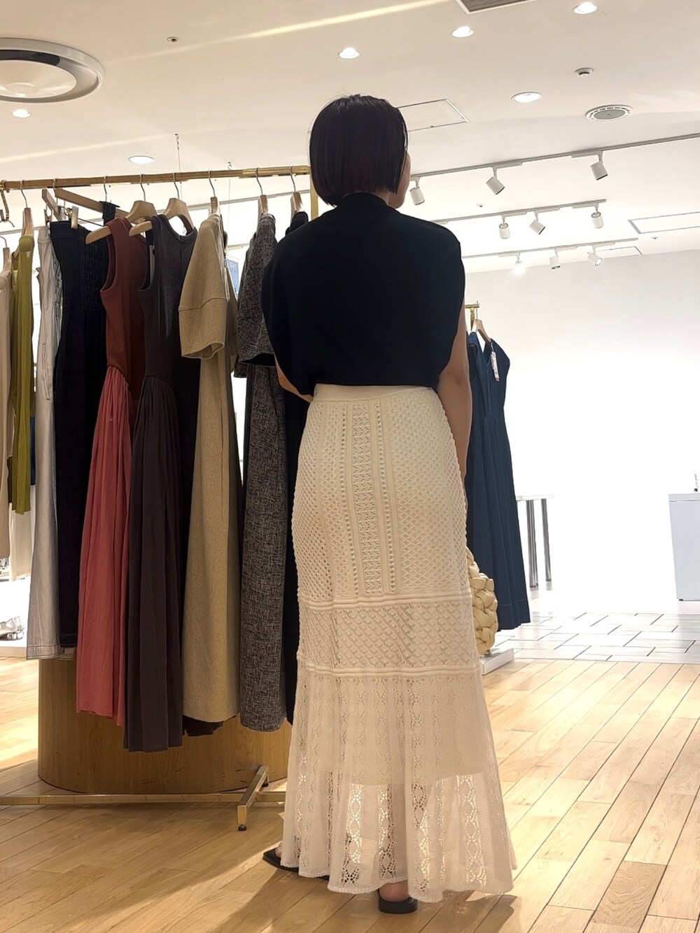 ホワイト系のスカート、ブラック系のサンダル、ホワイト系のハンドバッグを着用したレディースの夏コーディネートの3枚目の写真