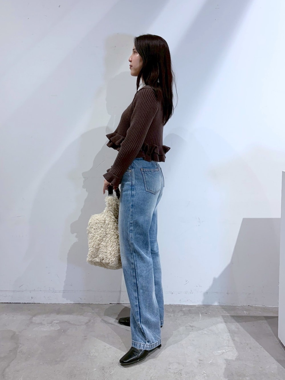 ブラウン系のニット/セーター、ブルー系のデニムパンツ、ブラック系のブーツを着用したレディースの夏コーディネートの2枚目の写真