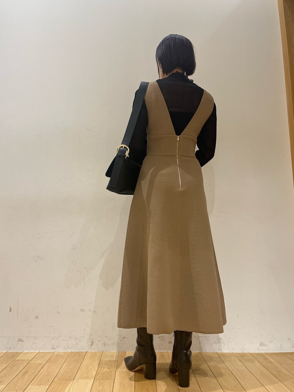 ブラック系のブーツ、ブラウン系のジャンパースカート、ブラック系のショルダーバッグを着用したレディースの秋コーディネートの3枚目の写真