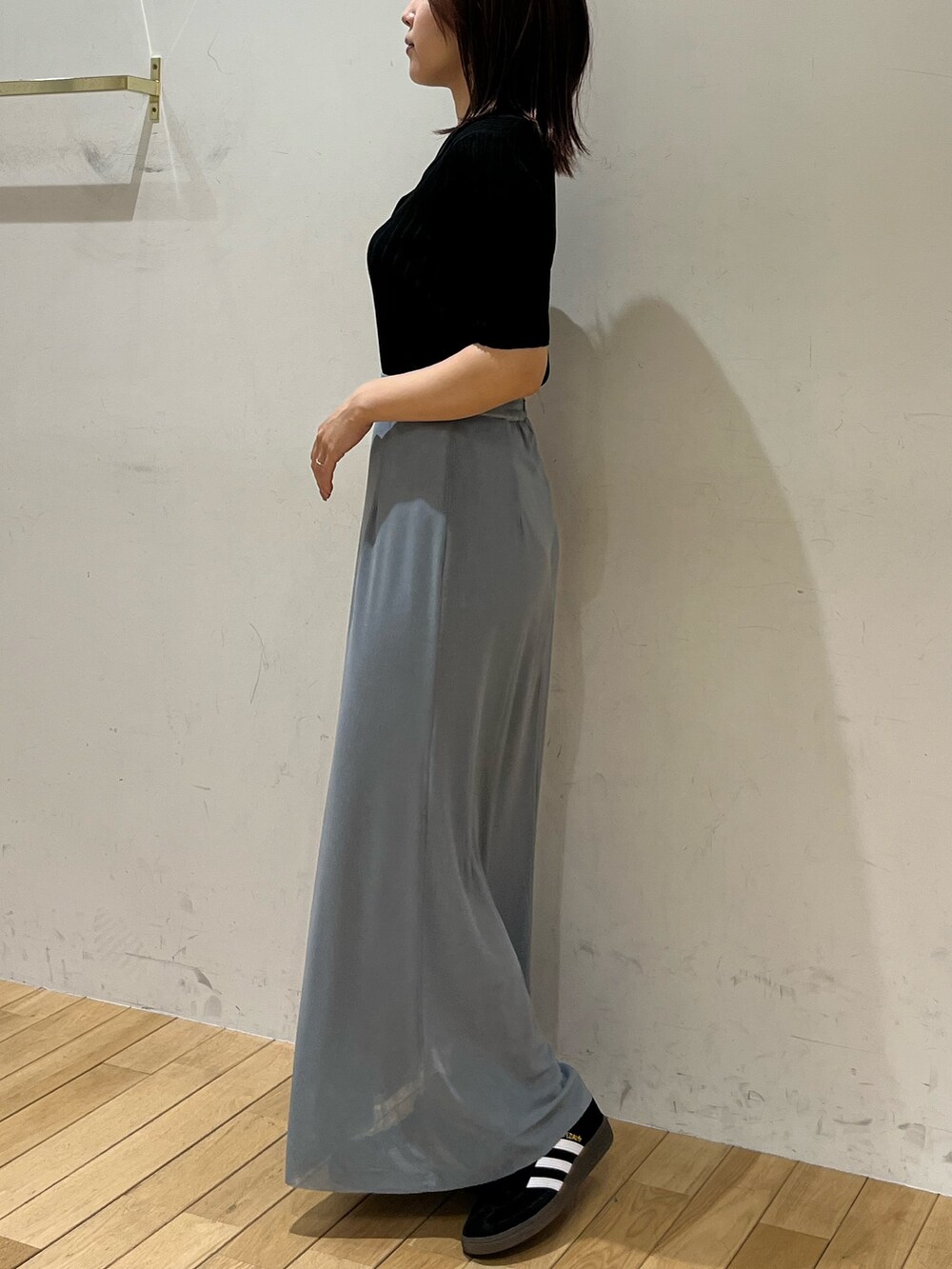 ブルー系のスカート、ブラック系のTシャツ/カットソー、ブラック系のスニーカーを着用したレディースの春コーディネートの2枚目の写真