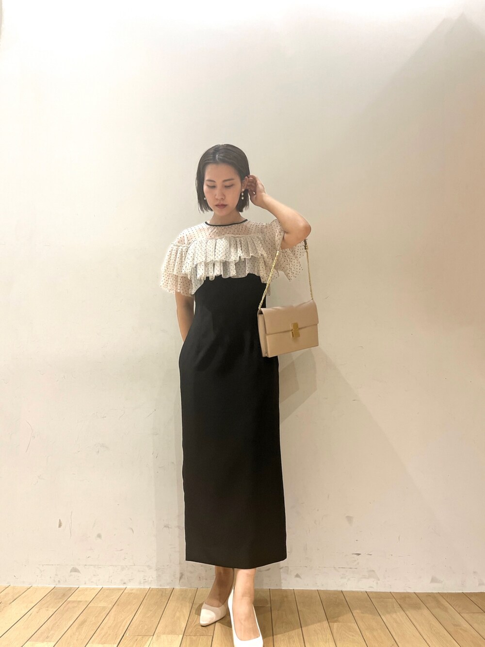 ブラウン系のパンプス、ブラウン系のクラッチバッグ、ブラック系のドレスを着用したレディースの春コーディネートの2枚目の写真