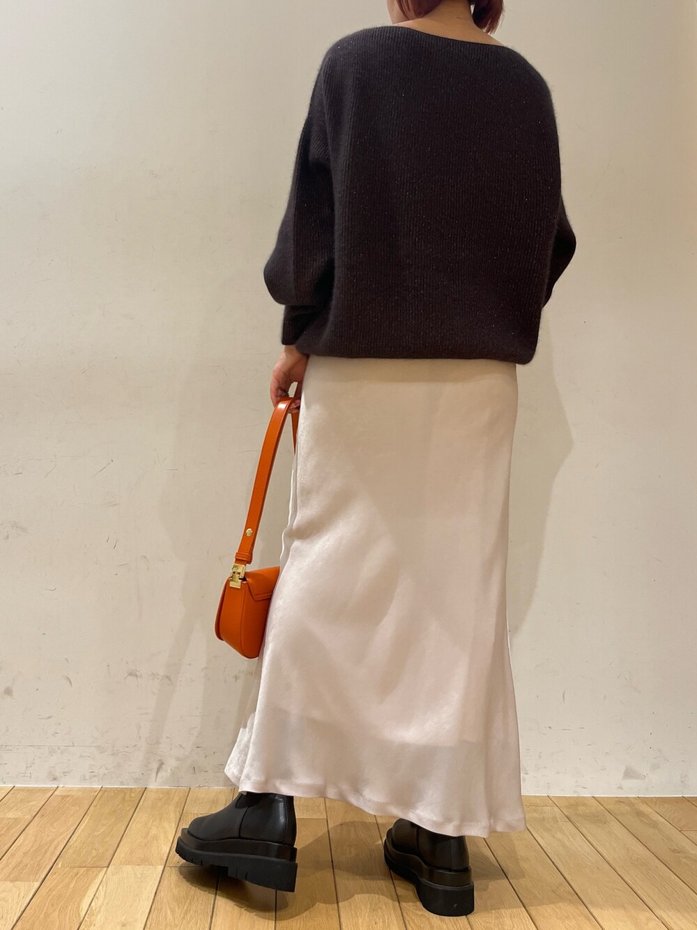 ホワイト系のスカート、オレンジ系のショルダーバッグ、ブラック系のブーツを着用したレディースの秋コーディネートの4枚目の写真