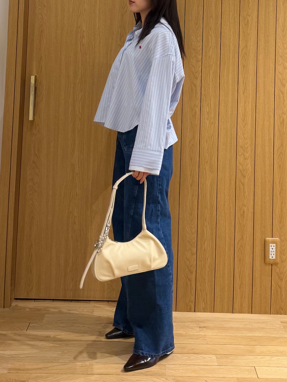 ブルー系のデニムパンツ、ブルー系のシャツ/ブラウス、ホワイト系のハンドバッグを着用したレディースの春コーディネートの2枚目の写真