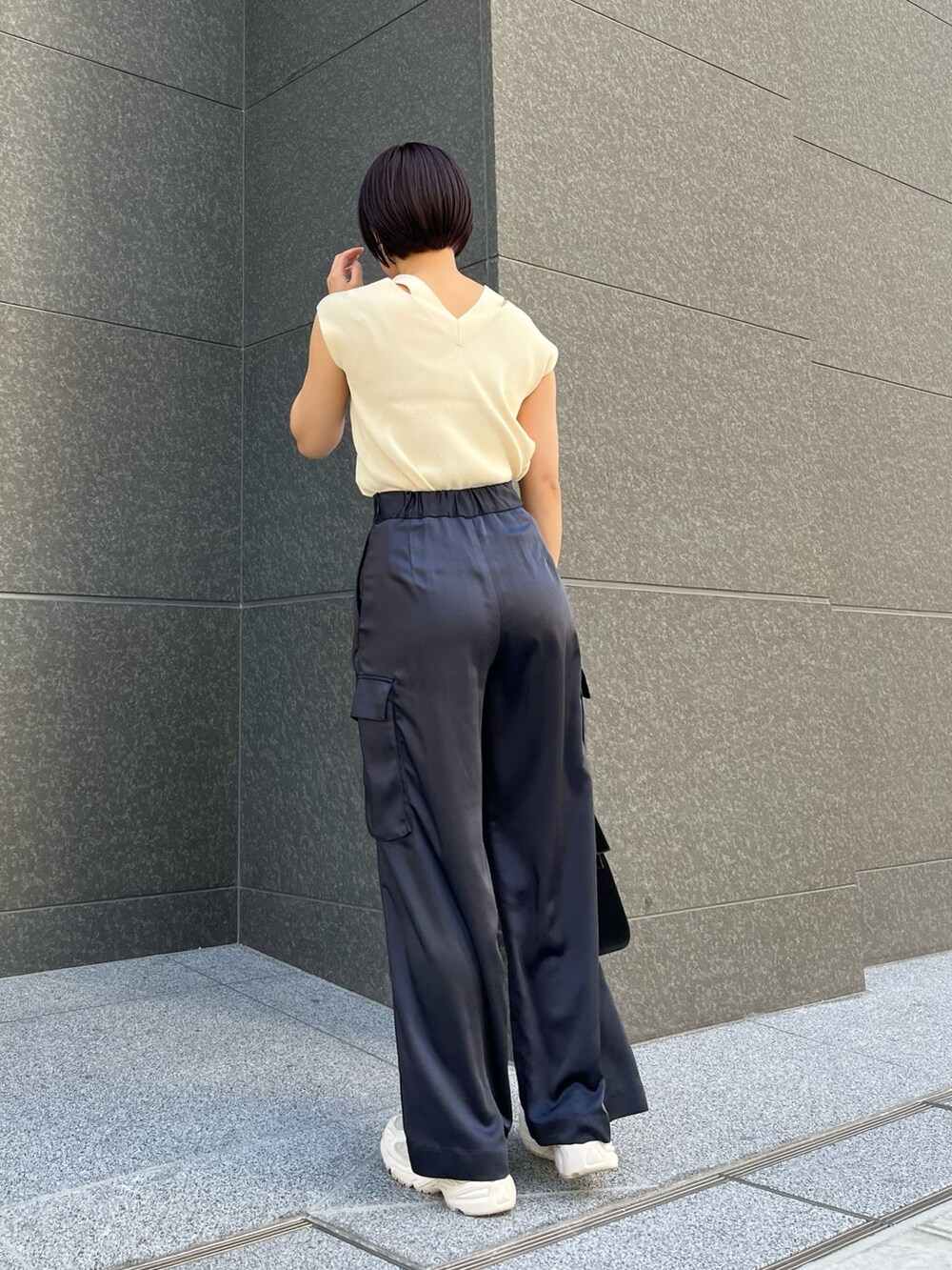 ブラック系のハンドバッグ、ブルー系のカーゴパンツ、ホワイト系のニット/セーターを着用したレディースの春コーディネートの4枚目の写真