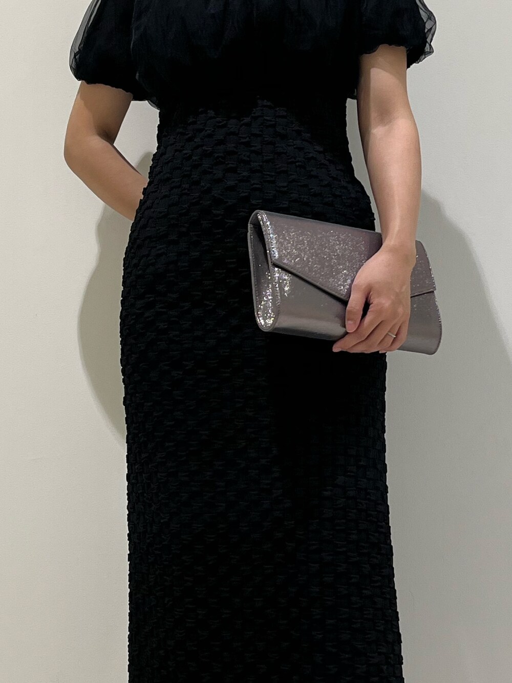 シルバー系のハンドバッグ、ブラック系のパンプス、ブラック系のドレスを着用したレディースの冬コーディネートの6枚目の写真