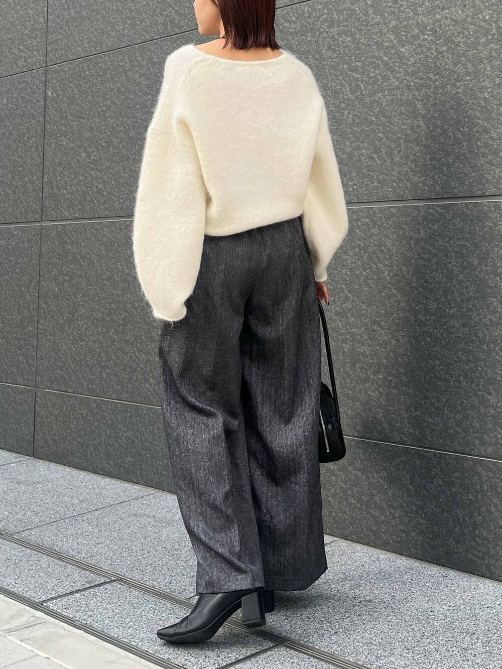 グレー系のその他パンツ、ホワイト系のニット/セーター、ブラック系のショルダーバッグを着用したレディースの冬コーディネートの3枚目の写真