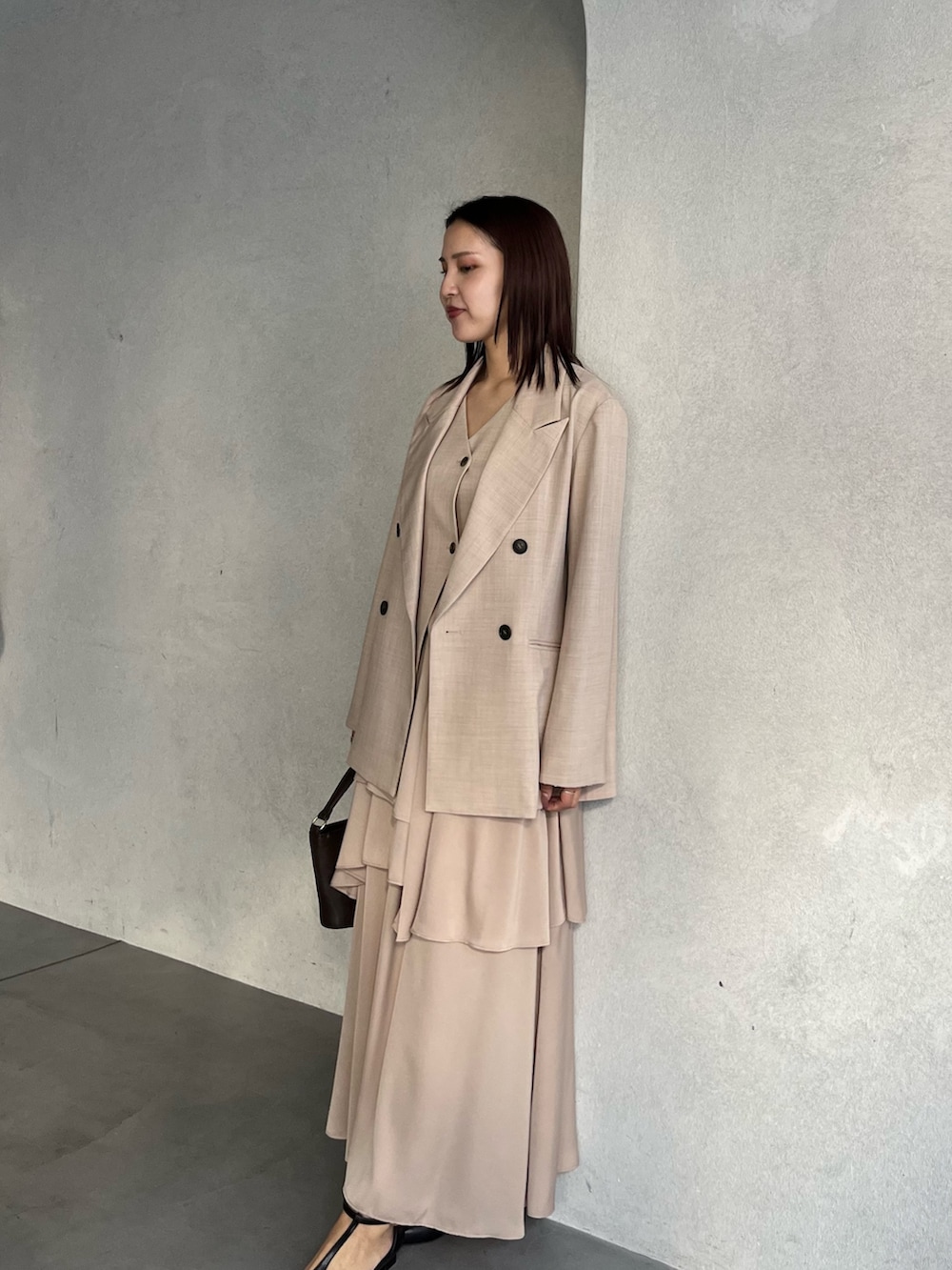 ベージュ系のテーラードジャケット、ベージュ系のワンピース、ブラウン系のハンドバッグを着用したレディースの冬コーディネートの4枚目の写真