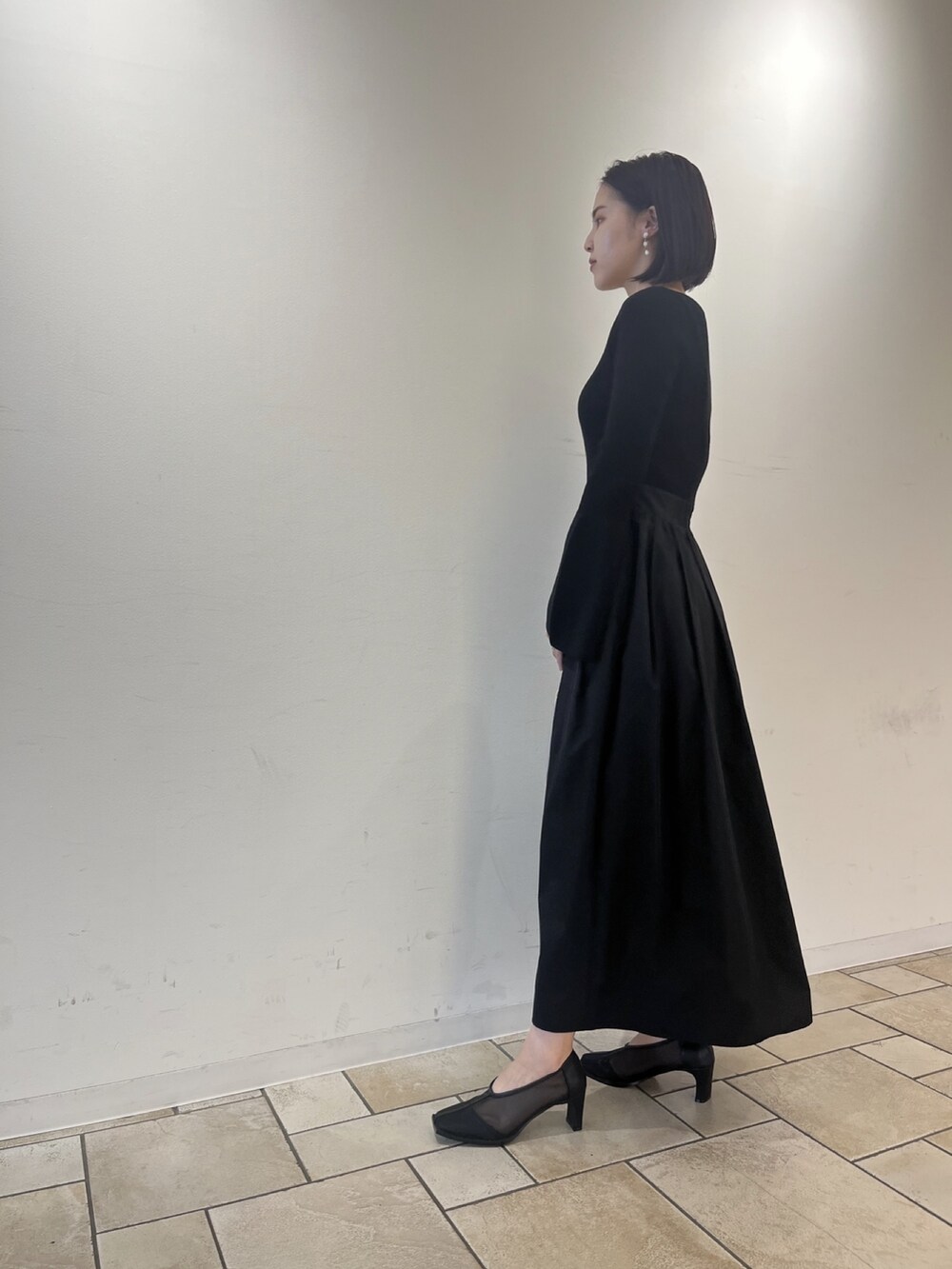 ブラック系のワンピース、ホワイト系のハンドバッグ、ブラック系のパンプスを着用したレディースの秋コーディネートの3枚目の写真