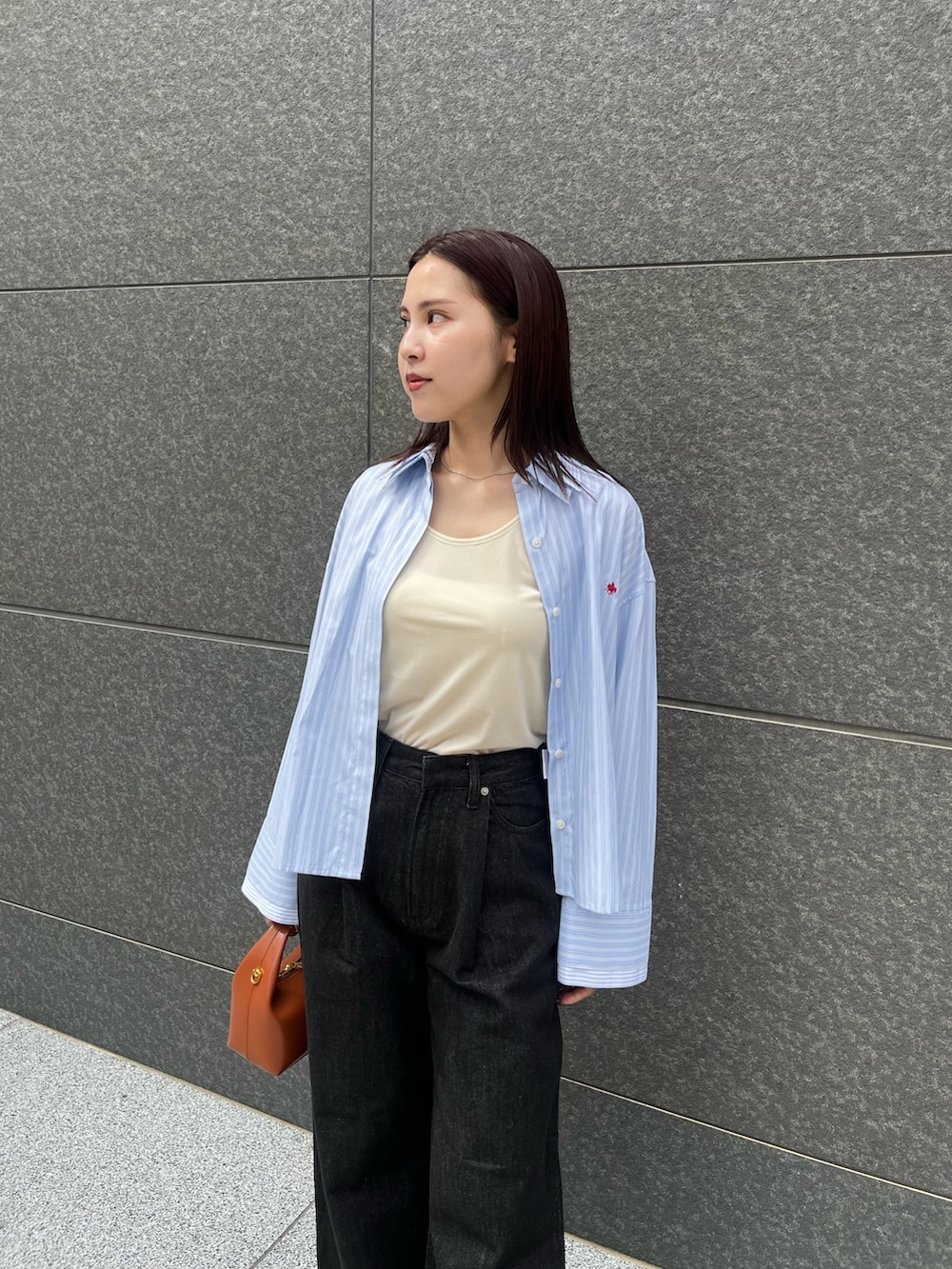 ブラック系のブーツ、ブラック系のデニムパンツ、レッド系のハンドバッグを着用したレディースの秋コーディネートの5枚目の写真