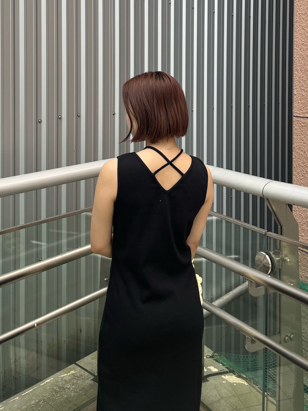 ブラック系のワンピース、ブラック系のサンダル、ホワイト系のハンドバッグを着用したレディースの夏コーディネートの4枚目の写真