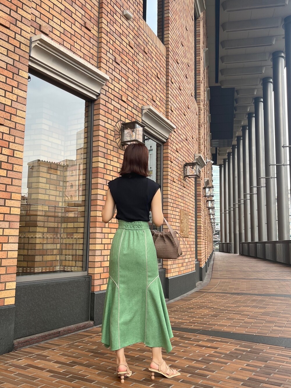 ブラック系のニット/セーター、グリーン系のスカート、ベージュ系のサンダルを着用したレディースの夏コーディネートの2枚目の写真