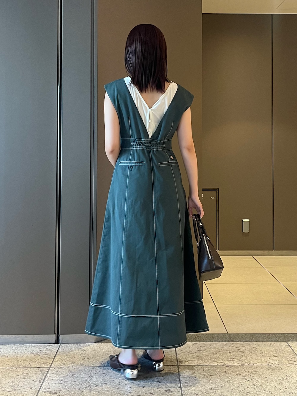 ブラウン系のパンプス、ブラウン系のボストンバッグ、ホワイト系のTシャツ/カットソーを着用したレディースの夏コーディネートの3枚目の写真