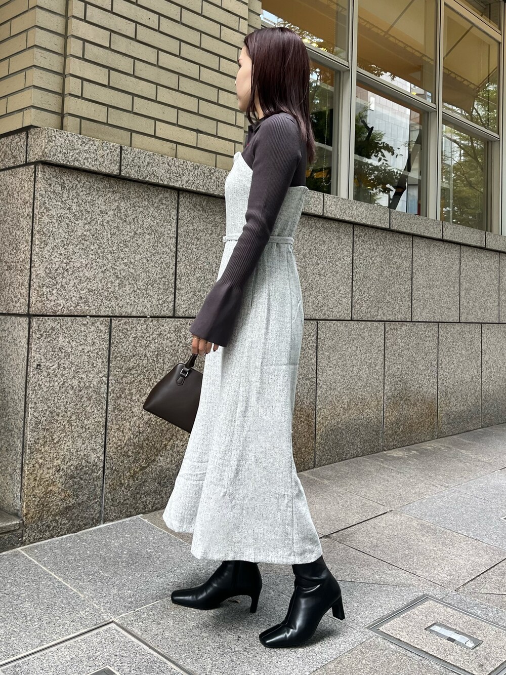 グレー系のワンピース、ブラウン系のボストンバッグ、ブラック系のブーツを着用したレディースの秋コーディネートの2枚目の写真