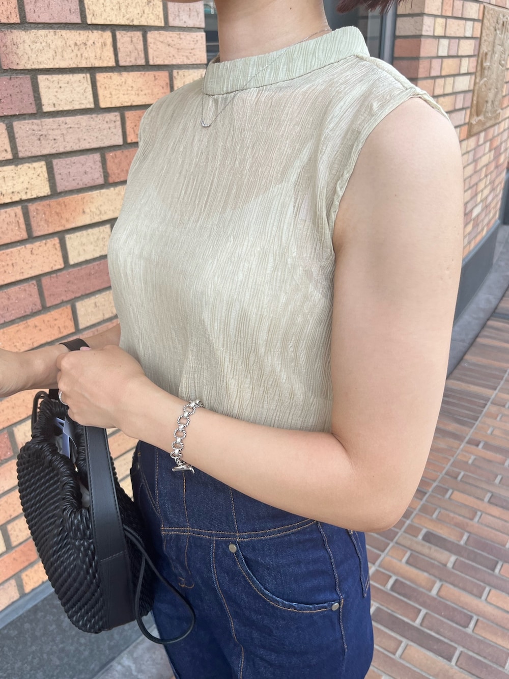 グリーン系のシャツ/ブラウス、ブルー系のデニムパンツ、ベージュ系のハンドバッグを着用したレディースの夏コーディネートの2枚目の写真