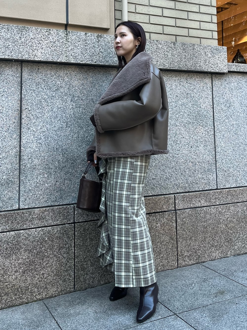 ベージュ系のムートンコート、ブラウン系のTシャツ/カットソー、ブラウン系のスカートを着用したレディースの冬コーディネートの2枚目の写真