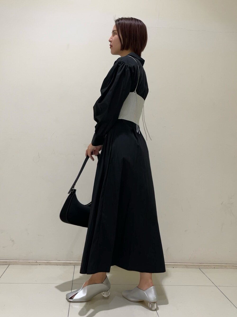 ブラック系のシャツワンピース、ブラック系のハンドバッグ、シルバー系のパンプスを着用したレディースの冬コーディネートの2枚目の写真