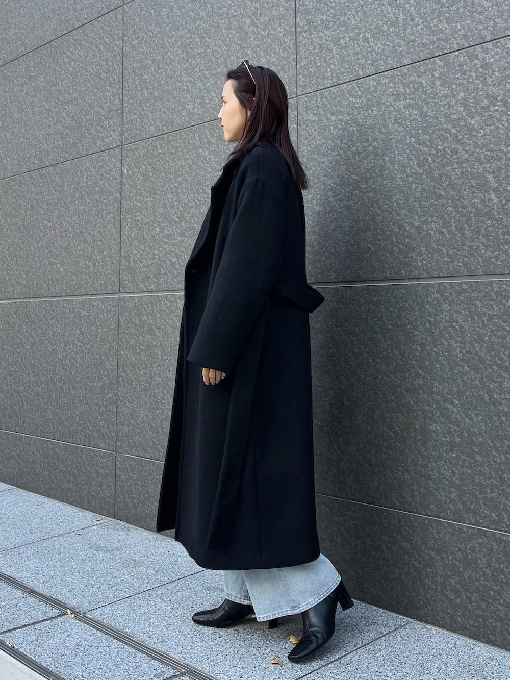 ブルー系のデニムパンツ、ブラウン系のハンドバッグ、ブラック系のブーツを着用したレディースの秋コーディネートの2枚目の写真