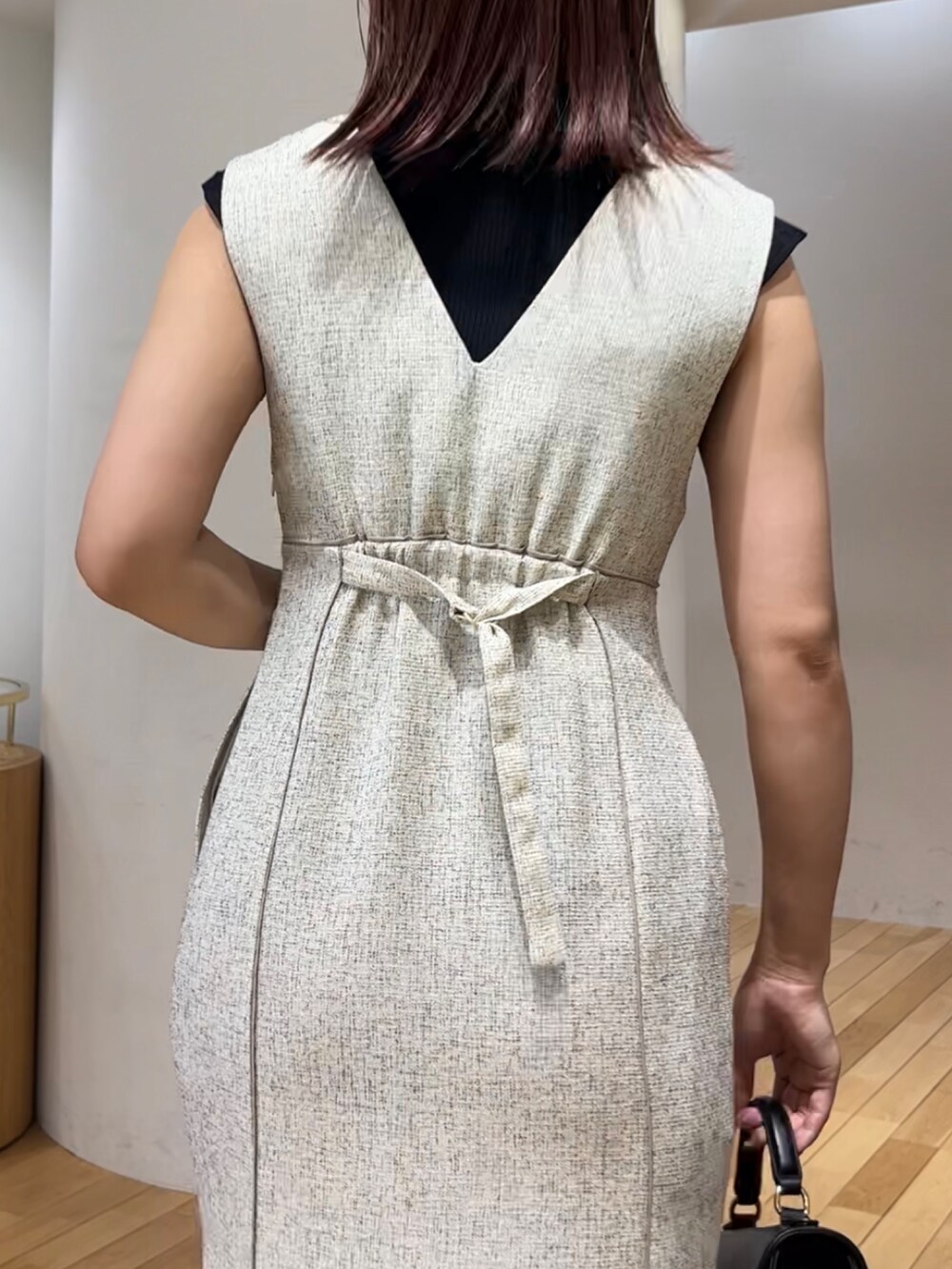 ブラック系のニット/セーター、ホワイト系のジャンパースカート、ブラック系のハンドバッグを着用したレディースの夏コーディネートの6枚目の写真